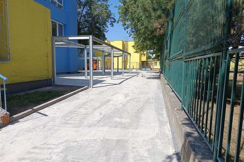 Zastřešená pergola podél chodníku vnitrobloku školy.